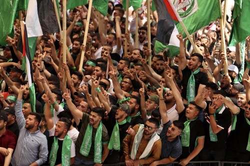 Palestinian students supporting the Islamic Hamas movement wave national and movement flags as they attend a debate ahead of student council elections at Birzeit University on the outskirts of Ramallah in the occupied West Bank, on May 17, 2022. (Photo by ABBAS MOMANI / AFP)