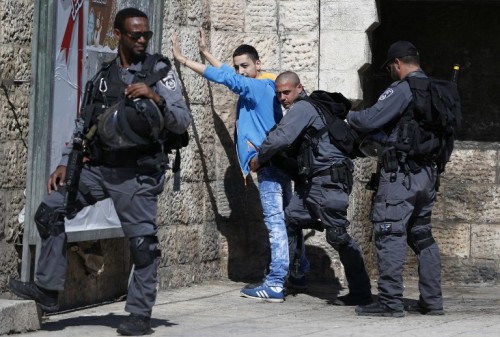 Israeli policemen body-check a Palestinian youth at Damascus Gate in the Old City of Jerusalem on February 17, 2016. / AFP / AHMAD GHARABLI