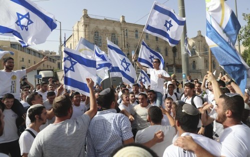 Israelis wave national flags during a Jerusalem Day march, in Jerusalem, Monday, May 10, 2021. Israeli police have changed the route of a contentious march by Jewish ultranationalists in Jerusalem, in an apparent attempt to avoid confrontations with Palestinian protesters. The original route had planned to go through Damascus Gate and into the Muslim Quarter of the Old City and on to the Western Wall. (AP Photo/Ariel Schalit)