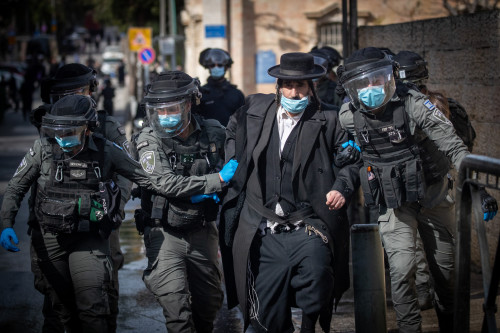 Israeli police officers clash with Ultra Orthodox Jewish men during enforcement of coronavirus emergency regulations, in Jerusalem, January 26, 2021. Photo by Yonatan Sindel/Flash90 *** Local Caption *** תקנות חירום הפגנה נגד מסיכות חרדים מפגינים