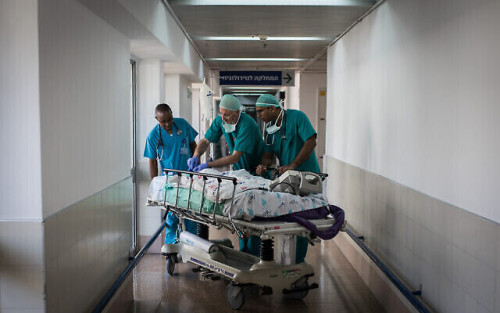 Doctors and nurses take two-year-old Zahran Khamis Haji to the emergency room for recovery after the infant underwent open-heart surgery at Wolfson Medical Center in Holon, Israel, on August 13, 2018. Zahran is one of several children with heart disease that were brought to Israel with the support of the Israeli humanitarian organization, Save a Child's Heart, to receive life-saving heart surgeries that are unavailble in their African home country. Photo by Hadas Parush/Flash90 *** Local Caption *** àîäåú àîà éìãéí úéðå÷åú çåìé ìá îçìú ìá îçìåú àôøé÷ä àôøé÷àéí ùãä úòåôä áï âåøéåï æðæéáø èðæðéä äöì ìéáå ùì éìã áéú éìãéí