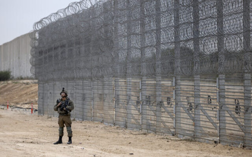 An Israeli soldier stands guard during a ceremony opening the newly completed underground barrier along the Israel-Gaza border, Tuesday, Dec. 7, 2021. Israel has announced the completion of the enhanced security barrier around the Gaza Strip designed to prevent militants from sneaking into the country. (AP Photo/Tsafrir Abayov)