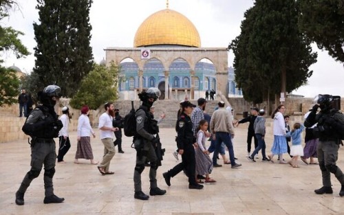 Israeli police accompany a group of Jewish visitors past the Dome of the Rock mosque at the al-Aqsa mosque compound in the Old City of Jerusalem on May 5, 2022. - Tourists and Jewish groups are allowed by Israeli police to enter the Al-Aqsa mosque compound for few a hours per day. The compound is revered as the site of two ancient Jewish temples, and home to al-Aqsa Mosque, Islam's third holiest site. Jews are allowed to enter the mosque compound but not to pray there. (Photo by AHMAD GHARABLI / AFP)