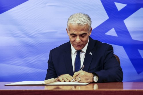 Israeli Prime Minister Yair Lapid signs the US-brokered deal setting a maritime border between Israel and Lebanon, at the Prime Minister's office in Jerusalem October 27, 2022. (Photo by RONEN ZVULUN / AFP)