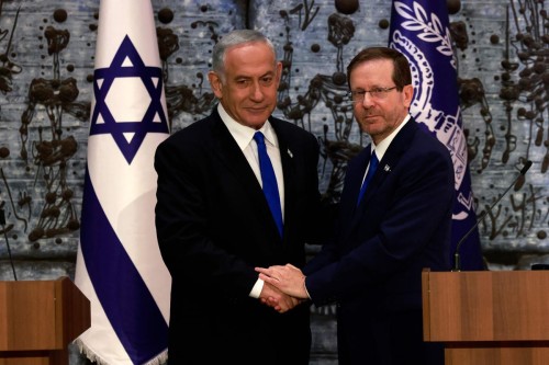 TOPSHOT - Israel's President Isaac Herzog (R) and Chairman Benjamin Netanyahu shake hands after the former tasked the latter with forming a new government, in Jerusalem, on November 13, 2022. - Hezog formally designated Benjamin Netanyahu to form a government, a victory for the former veteran prime minister who had vowed to return to power. (Photo by Menahem KAHANA / AFP)