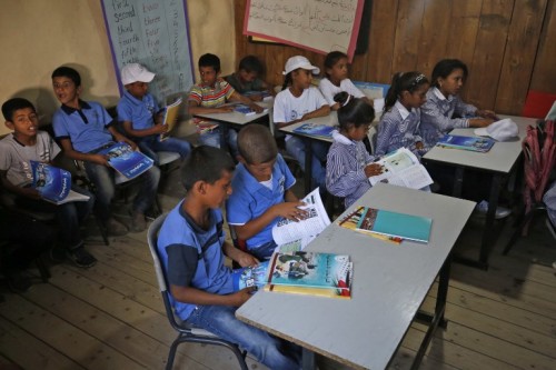 Palestinian children sit in a classroom after the early start of classes at a school in the Bedouin village of Khan al-Ahmar in the occupied West Bank on July 16, 2018. Israel's Supreme Court previously temporarily blocked the demolition of the Palestinian Bedouin village, located near several major Israeli settlements and close to a highway leading to the Dead Sea, following growing international concerns over the move. / AFP PHOTO / ABBAS MOMANI / The erroneous mention[s] appearing in the metadata of this photo by ABBAS MOMANI has been modified in AFP systems in the following manner: ommission of [during the Palestinian Prime Minister's visit to the village]. Please immediately remove the erroneous mention[s] from all your online services and delete it (them) from your servers. If you have been authorized by AFP to distribute it (them) to third parties, please ensure that the same actions are carried out by them. Failure to promptly comply with these instructions will entail liability on your part for any continued or post notification usage. Therefore we thank you very much for all your attention and prompt action. We are sorry for the inconvenience this notification may cause and remain at your disposal for any further information you may require.