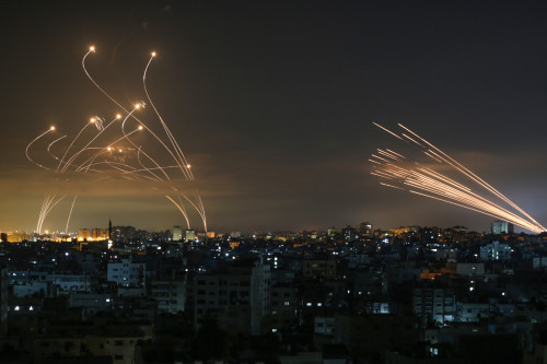 The Israeli Iron Dome missile defence system (L) intercepts rockets (R) fired by the Hamas movement towards southern Israel from Beit Lahia in the northern Gaza Strip as seen in the sky above the Gaza Strip overnight on May 14, 2021. - Israel bombarded Gaza with artillery and air strikes on Friday, May 14, in response to a new barrage of rocket fire from the Hamas-run enclave, but stopped short of a ground offensive in the conflict that has now claimed more than 100 Palestinian lives. As the violence intensified, Israel said it was carrying out an attack "in the Gaza Strip" although it later clarified there were no boots on the ground. (Photo by ANAS BABA / AFP)