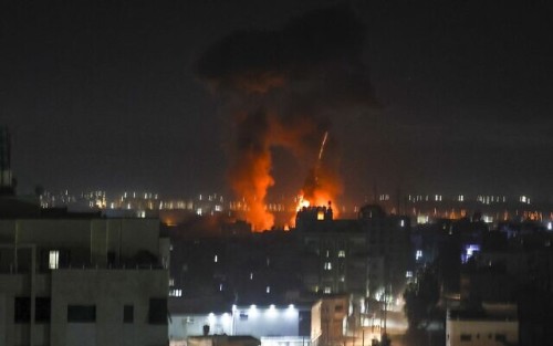 Explosions light-up the night sky above buildings in Gaza City as Israeli forces shell the Palestinian enclave, early on June 16, 2021. (Photo by MAHMUD HAMS / AFP)