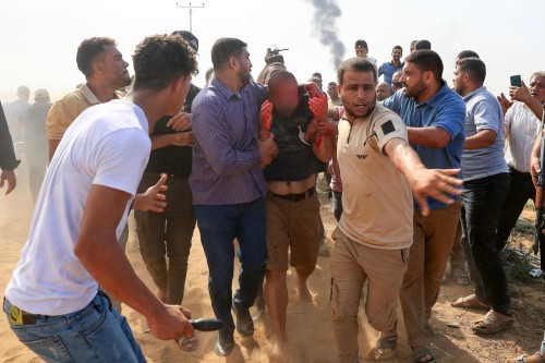 Palestinians lead a reportedly captured and injured Israeli man, in Khan Yunis in the southern Gaza Strip, on October 7, 2023. Palestinian militants had begun a "war" against Israel which they infiltrated by air, sea and land from the blockaded Gaza Strip on October 7, Israeli officials said, a major escalation in the Israeli-Palestinian conflict. (Photo by AFP)