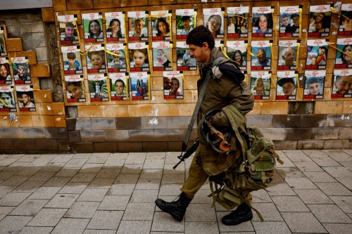 A soldier walks past a wall with pictures of hostages kidnapped in the deadly October 7 attack on Israel by the Palestinian Islamist group Hamas, in Tel Aviv, Israel, January 31, 2024. REUTERS/Susana Vera     TPX IMAGES OF THE DAY