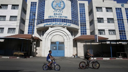 Children ride their bicycles in front of a health centre run by the United Nations Relief and Works Agency (UNRWA) in Gaza City on October 2, 2018, closed in protest against job cuts announced by the UNRWA. Earlier this year, the United States, by far the biggest contributor to the agency, announced it was halting its funding to the organisation, which it labelled "irredeemably flawed". (Photo by SAID KHATIB / AFP)