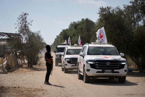 ICRC vehicles transporting released Israeli hostages head toward the Israeli border drive by a Hamas gunman in Khan Younis, southern Gaza Strip, Monday, Oct. 13, 2025. (AP Photo/Jehad Alshrafi)