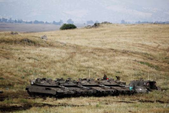 Israeli soldiers stand on tanks near the Israeli side of the border with Syria in the Israeli-occupied Golan Heights