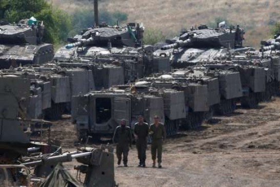 Israeli soldiers walk among armored vehicles in the Israeli-occupied Golan Heights